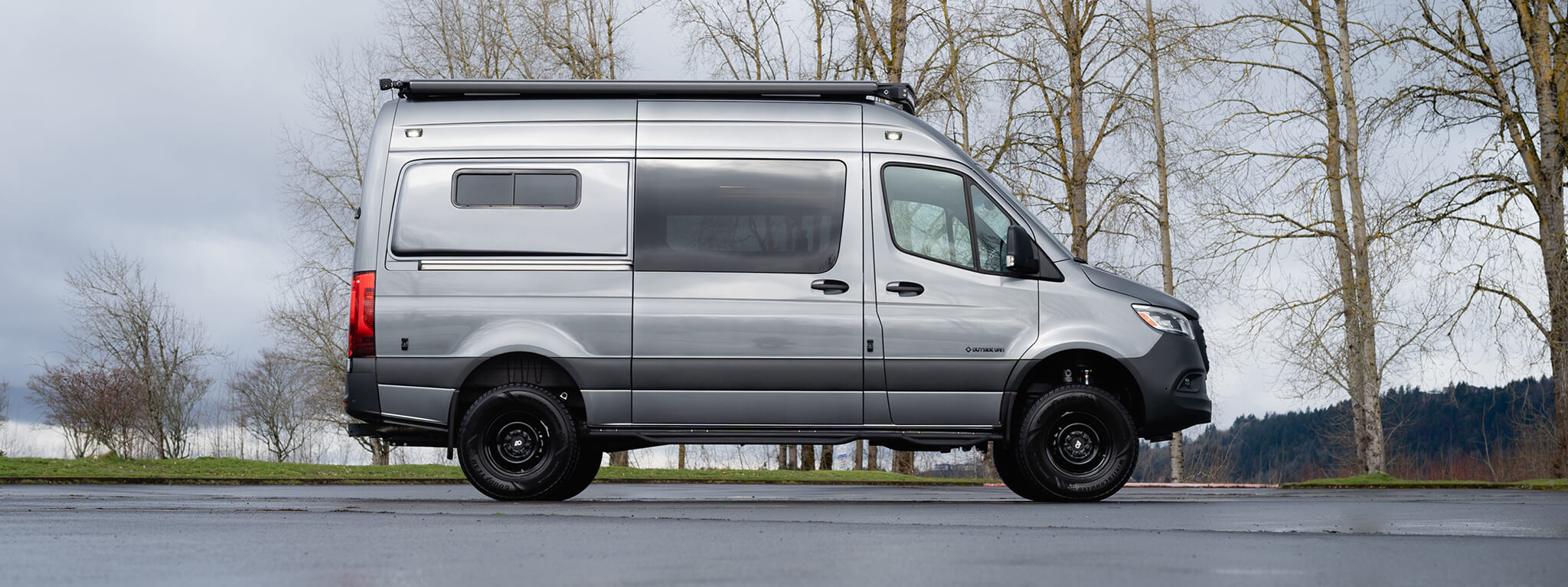 Silver adventure van with slider door closed in a parking lot