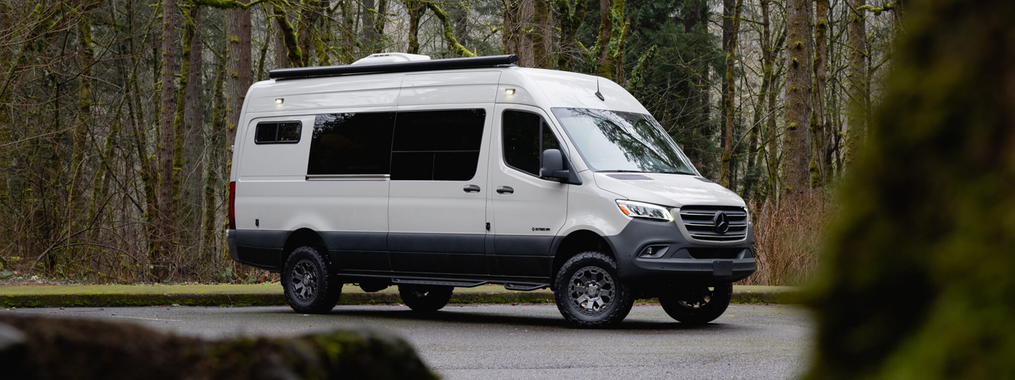 White van in a forested parking lot