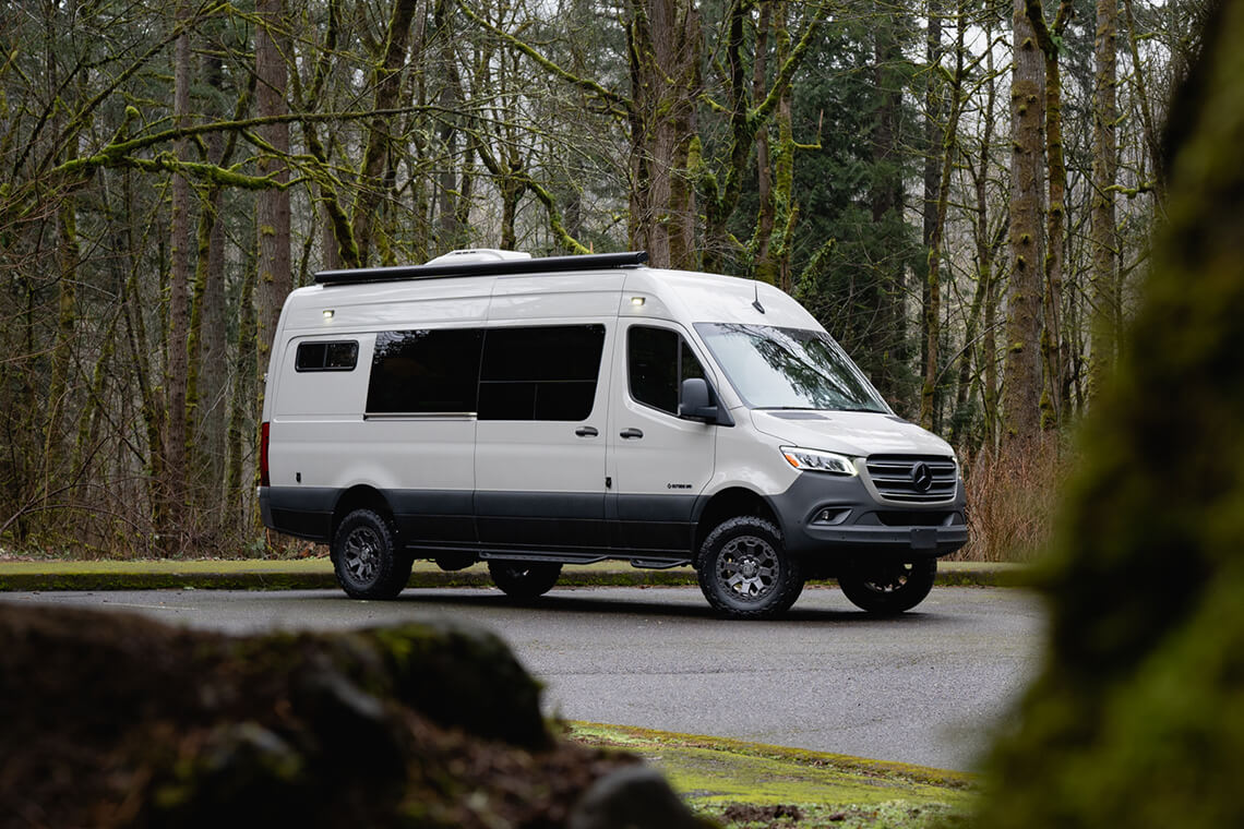 White van in a forested parking lot