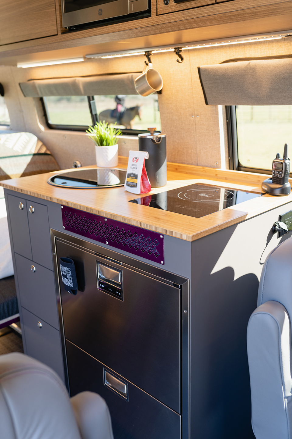 Driver-side galley kitchen featuring an induction stove, dual stainless steel refrigerator, drawers, sink, and faucet