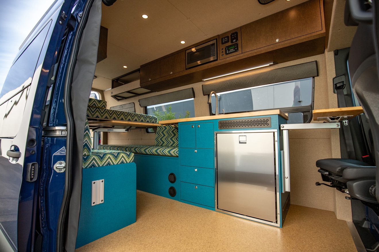 Custom interior with bed, kitchen, and bench inside converted sprinter van