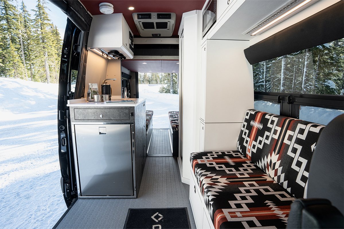 Sprinter van interior with stainless steel refrigerator in passenger slider door and custom upholstery