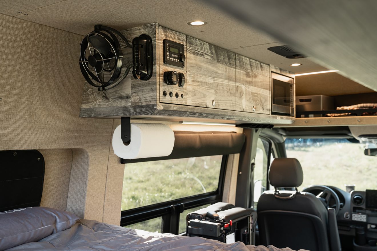 Interior sprinter van with enclosed overhead cabinetry, microwave, and small fan