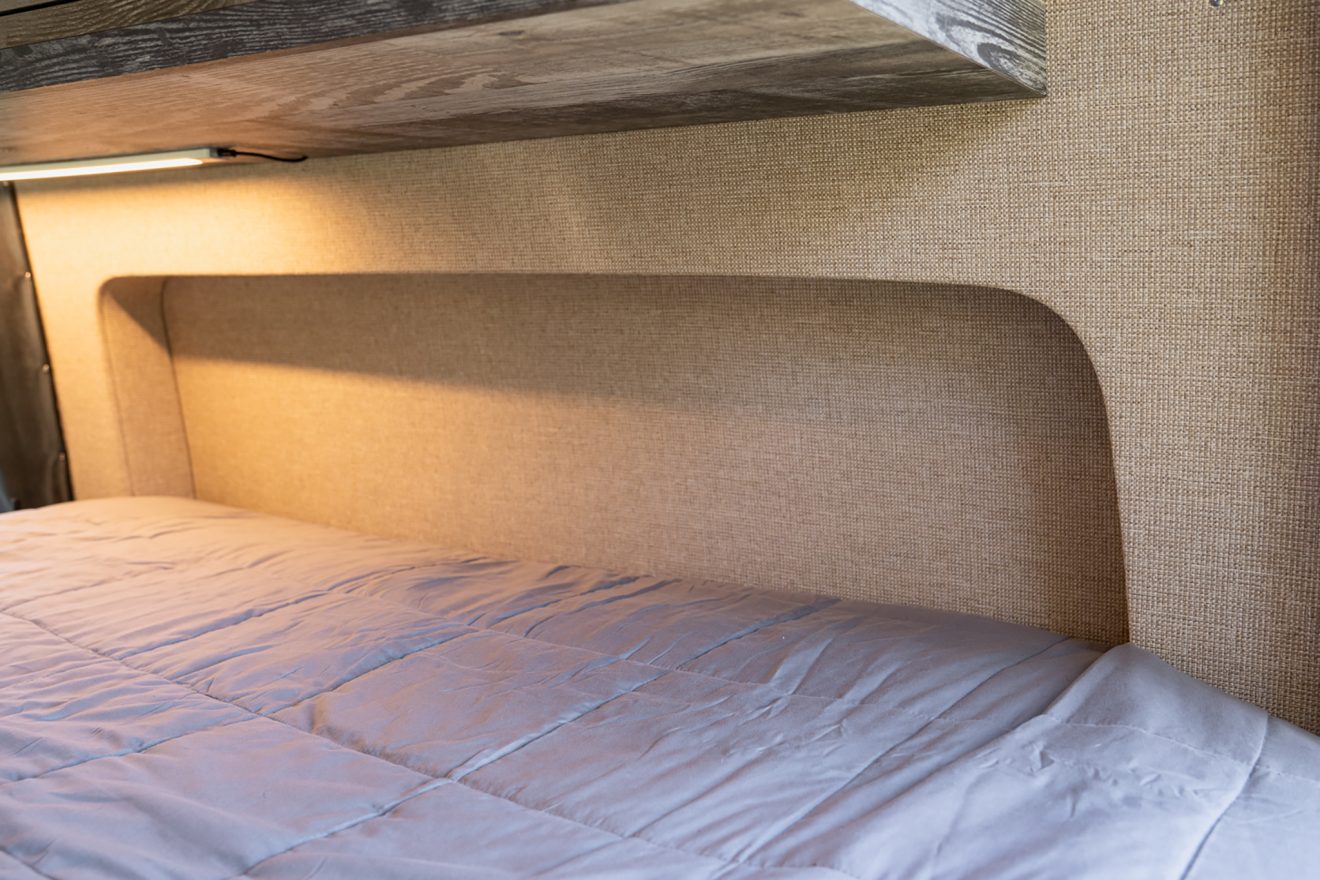 Interior Sprinter van bed with purple comforter and flared panel sleep area