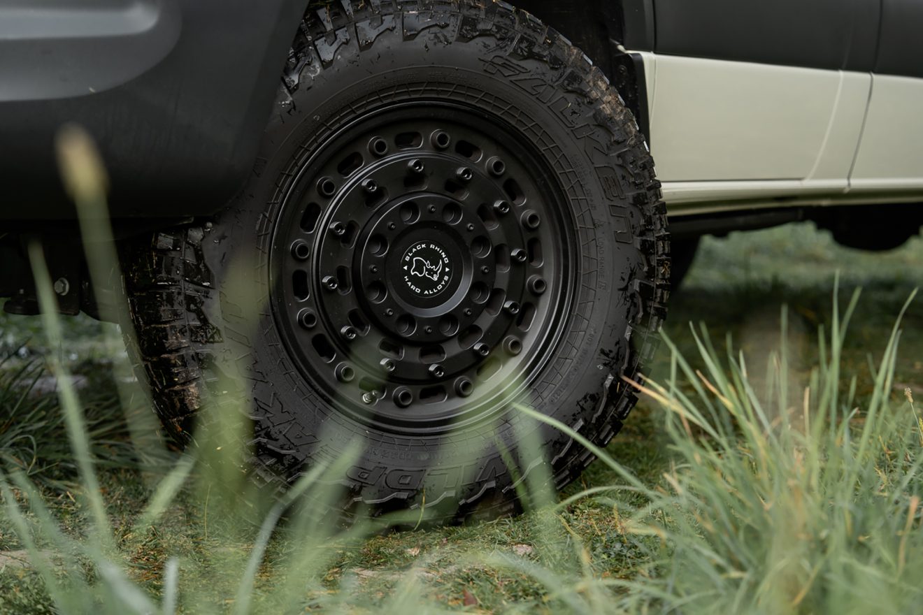 Exterior large black van wheel and all-terrain tire in grass
