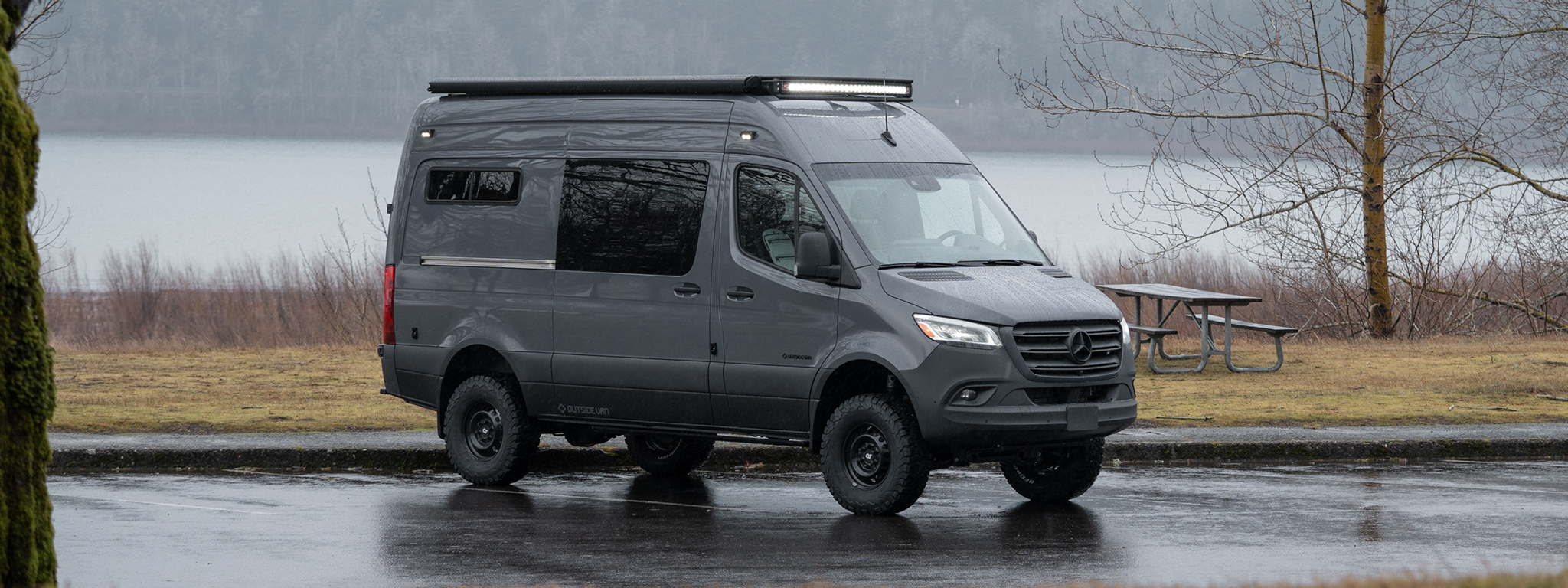 custom 2022 Mercedes-Benz Sprinter 144 high roof van 4WD seat two sleep two in a wet parking lot