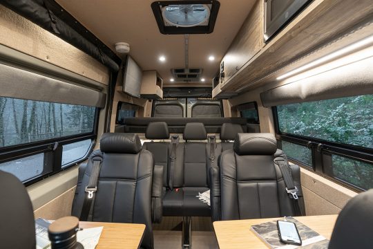 Interior of a van with one row of dot-approved captain's chairs and one travois bench seat travel approved