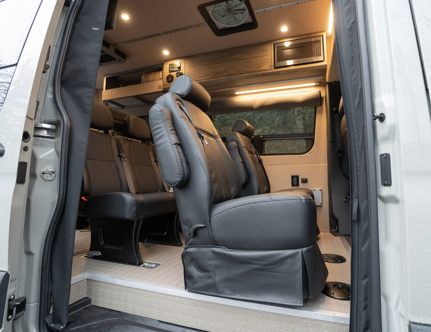 Interior of a van with one row of dot-approved captain's chairs and one travois bench seat travel approved