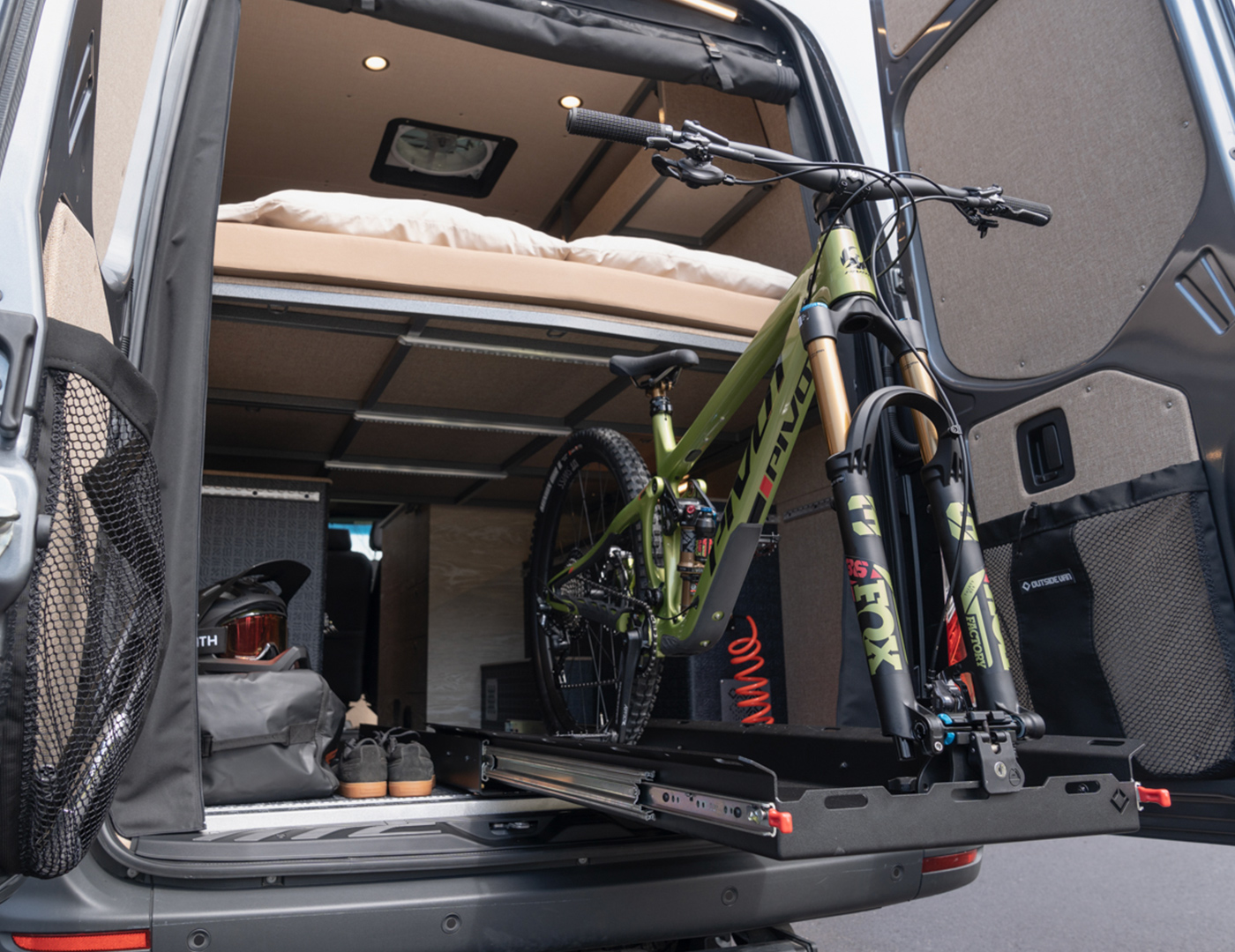 Green pivot mountain bike on an outside van gear glider slide out tray in the garage of a custom converted sprinter van