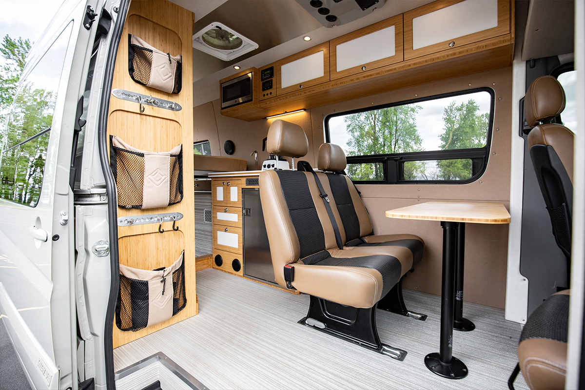 Wide interior photo of 170 Mercedes Benz 4wd sprinter. Hemp tan interior with leather seating for 2 with bamboo shower and suede ceiling
